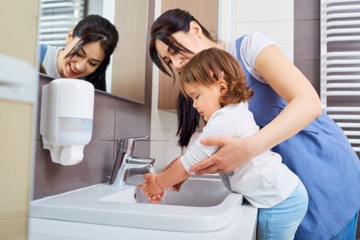 Parent helping a child gently wash their hand after a cryotherapy blister breaks