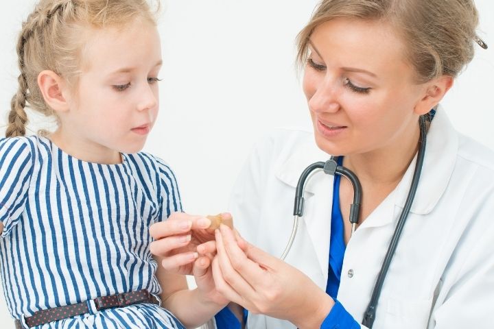 Pediatrician checking and covering a child’s finger after wart cryotherapy treatment