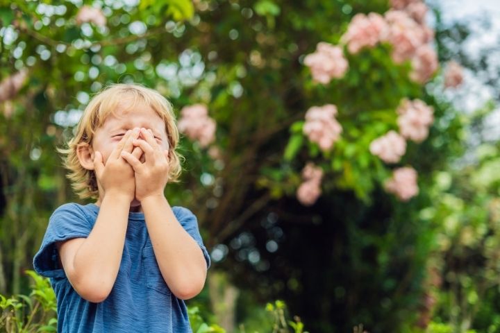 Child outdoors near flowers that can contribute to allergy and asthma symptoms